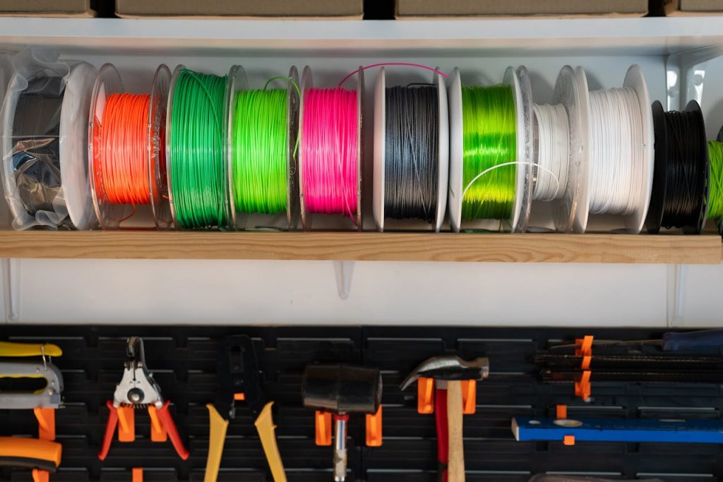 pexels photo 19376296 A variety of colorful filament spools and tools organized on a workshop shelf, ideal for 3D printing enthusiasts.